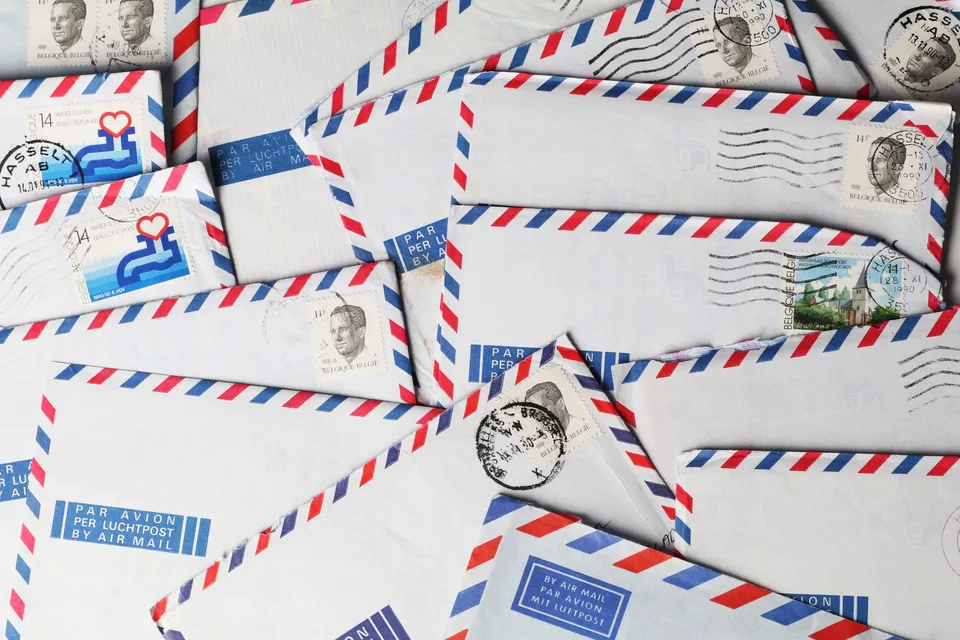 A pile of red-and-blue-bordered airmail envelopes with canceled postage stamps